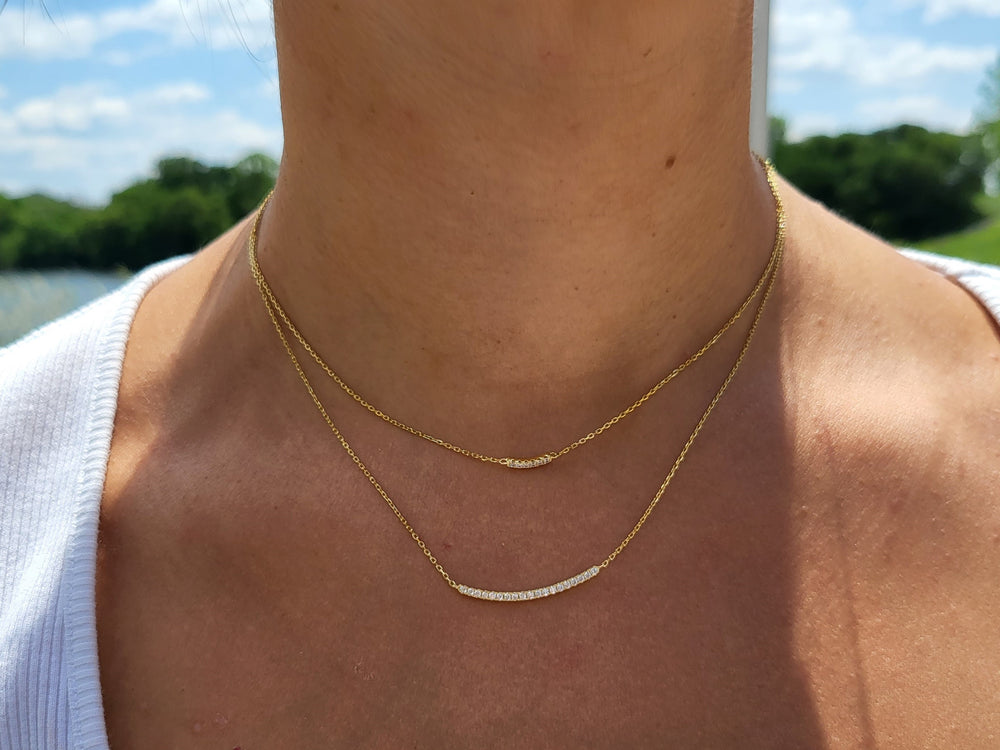 Get ready to turn heads with our exquisite double strand necklace! Crafted with love and plated in 14 karat gold, this stunning piece features curved cubic zirconia bars that radiate elegance. With a lobster clasp closure, it's perfect for any occasion. Elevate your style with this must-have accessory!