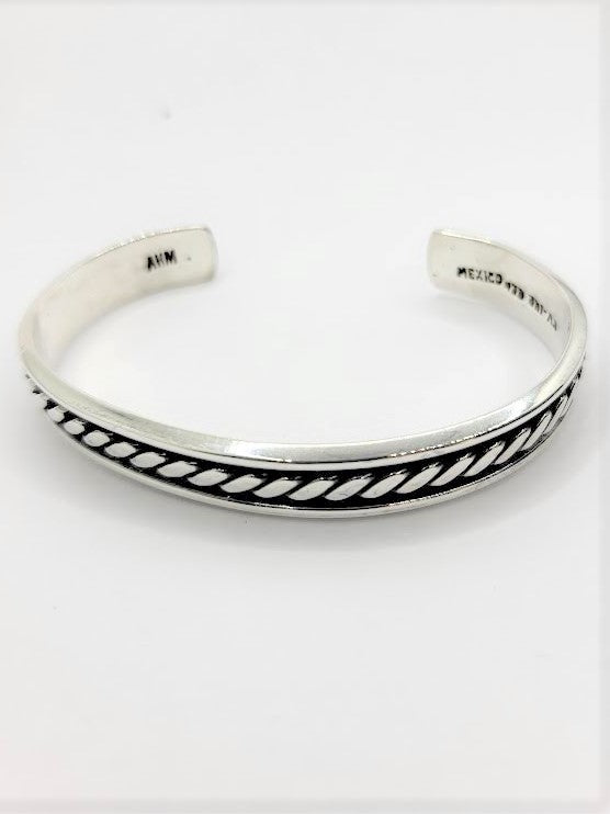 Experience the epitome of luxury with our exquisite Stud Muffin cuff bracelet. Meticulously handcrafted from the finest .925 sterling silver, its captivating rope design commands attention. Measuring a generous 62mm x 47mm wide, this opulent piece exudes sophistication. The alluring oxidized finish adds depth and character, while the polished silver radiates with a dazzling shine. Elevate your style by pairing it with our exclusive collection of men's oxidized sterling silver jewelry.