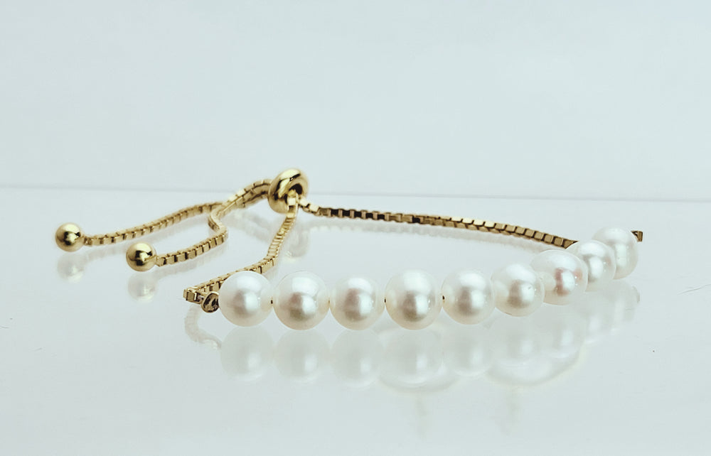 Indulge in luxury with our adjustable 14k gold plated sterling silver bolo bracelet, adorned with 9 white cultured freshwater pearls. Valuable and versatile, it pairs perfectly with our gold and pearl collection.