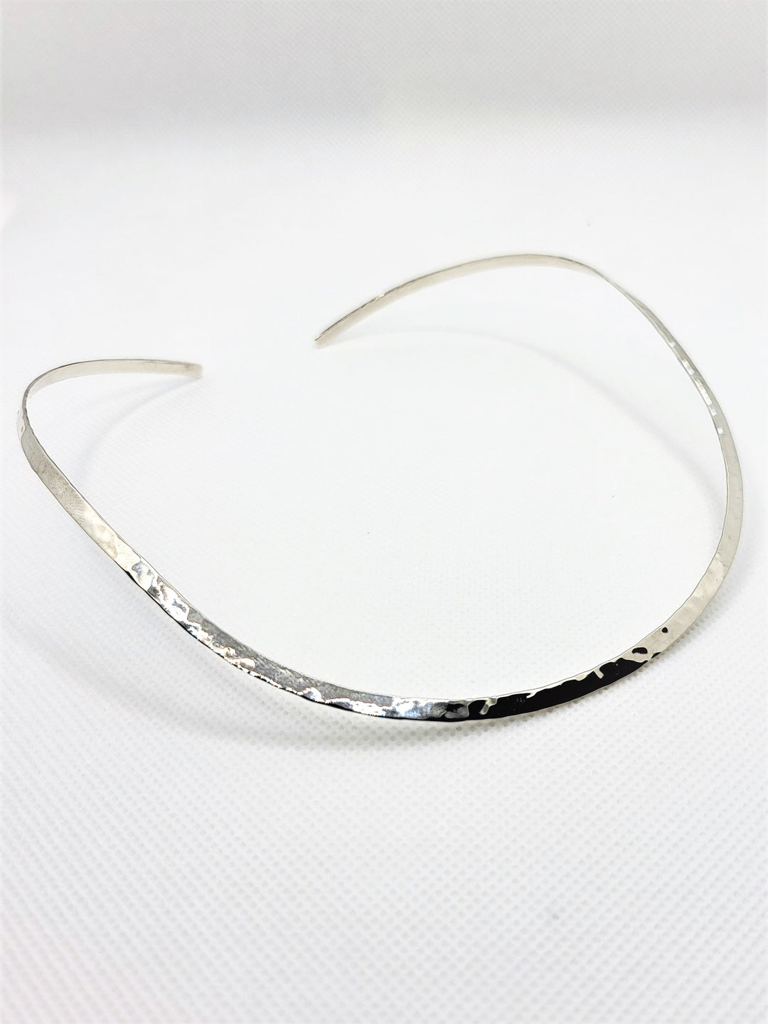 Indulge in the exquisite allure of our 3mm hammered open back collar necklace, crafted from .925 sterling silver. Its delicate weight will make you forget you're wearing it, while its stunning design draws the gaze of all who behold it. Pair it with our other hammered sterling silver pieces for a truly luxurious look.