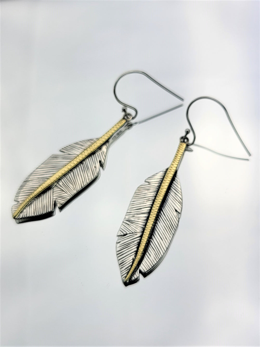 Elevate your style with these exquisite feather drop earrings featuring gold plated accents. A must-have addition to your collection.