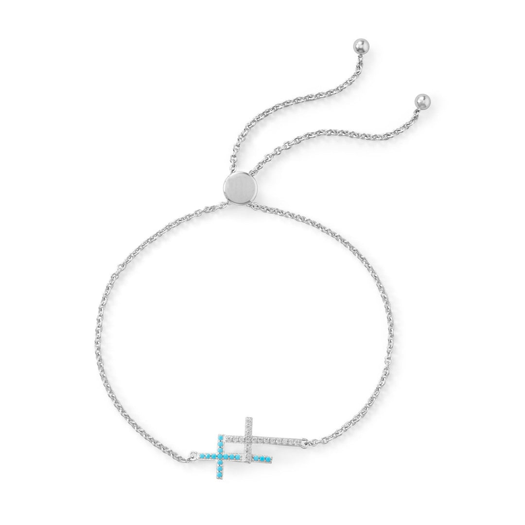 Adjustable rhodium plated sterling silver double Cubic Zirconia cross bracelet. The double cross design is approximately 11.5mm x 18.5mm. The crosses are clear Signity Cubic Zirconia and teal Cubic Zirconia. The bracelet adjusts to 9.5" with a 6.5mm silver bead. .925 Sterling Silver